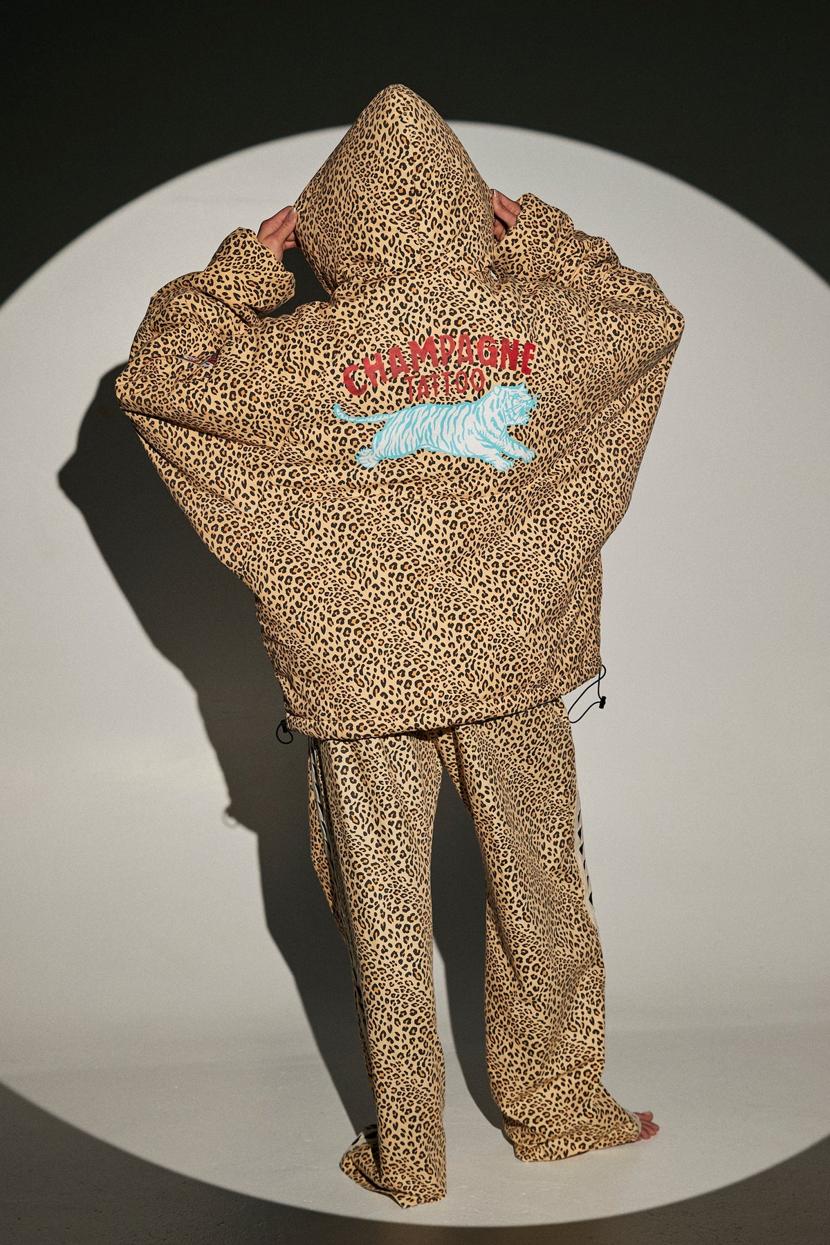 achterkant van de puffer met champagne tiger patch, capuchon op gezet