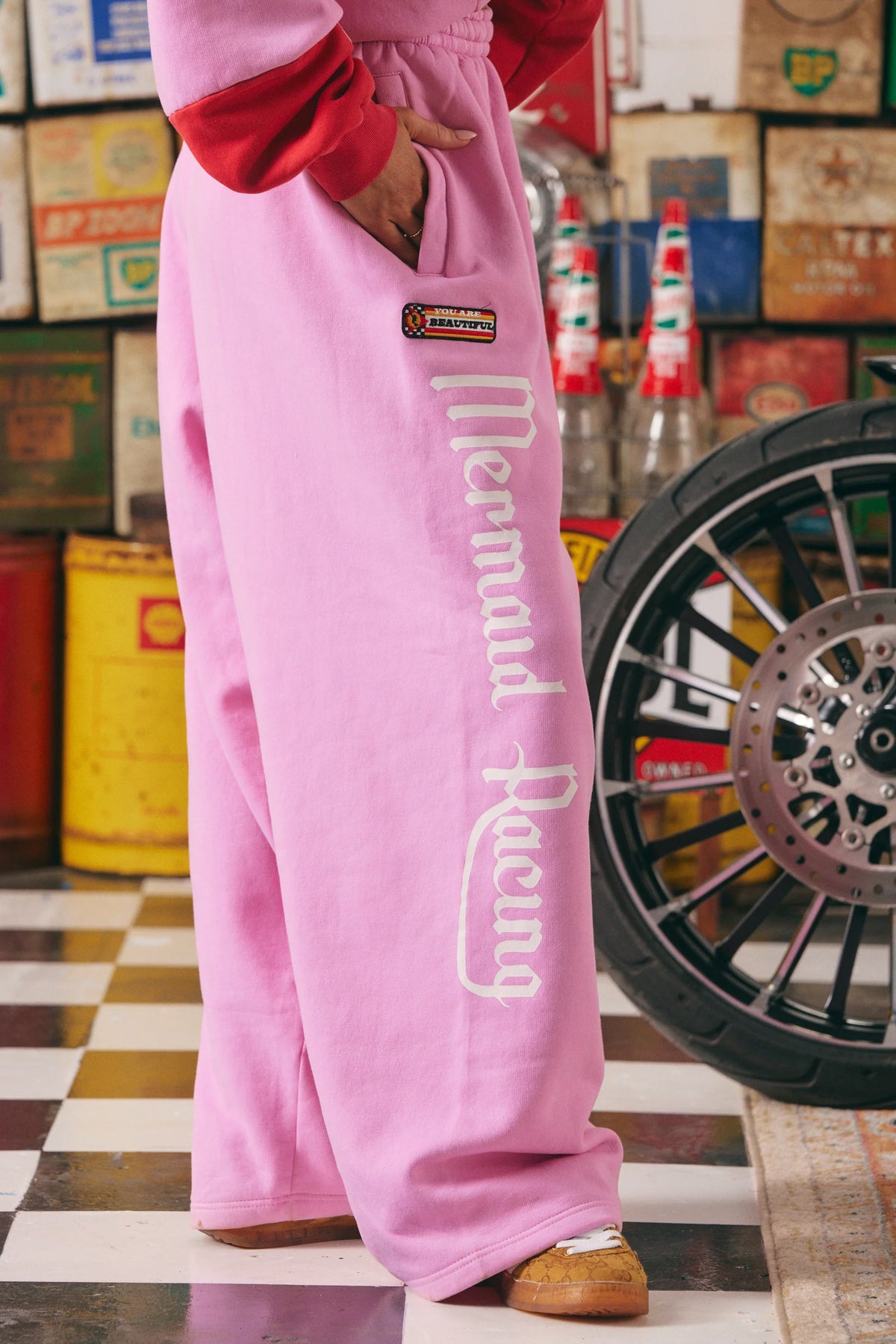 detail van de zijkant met mermaid racing print en badge op roze wide-leg sweatpants