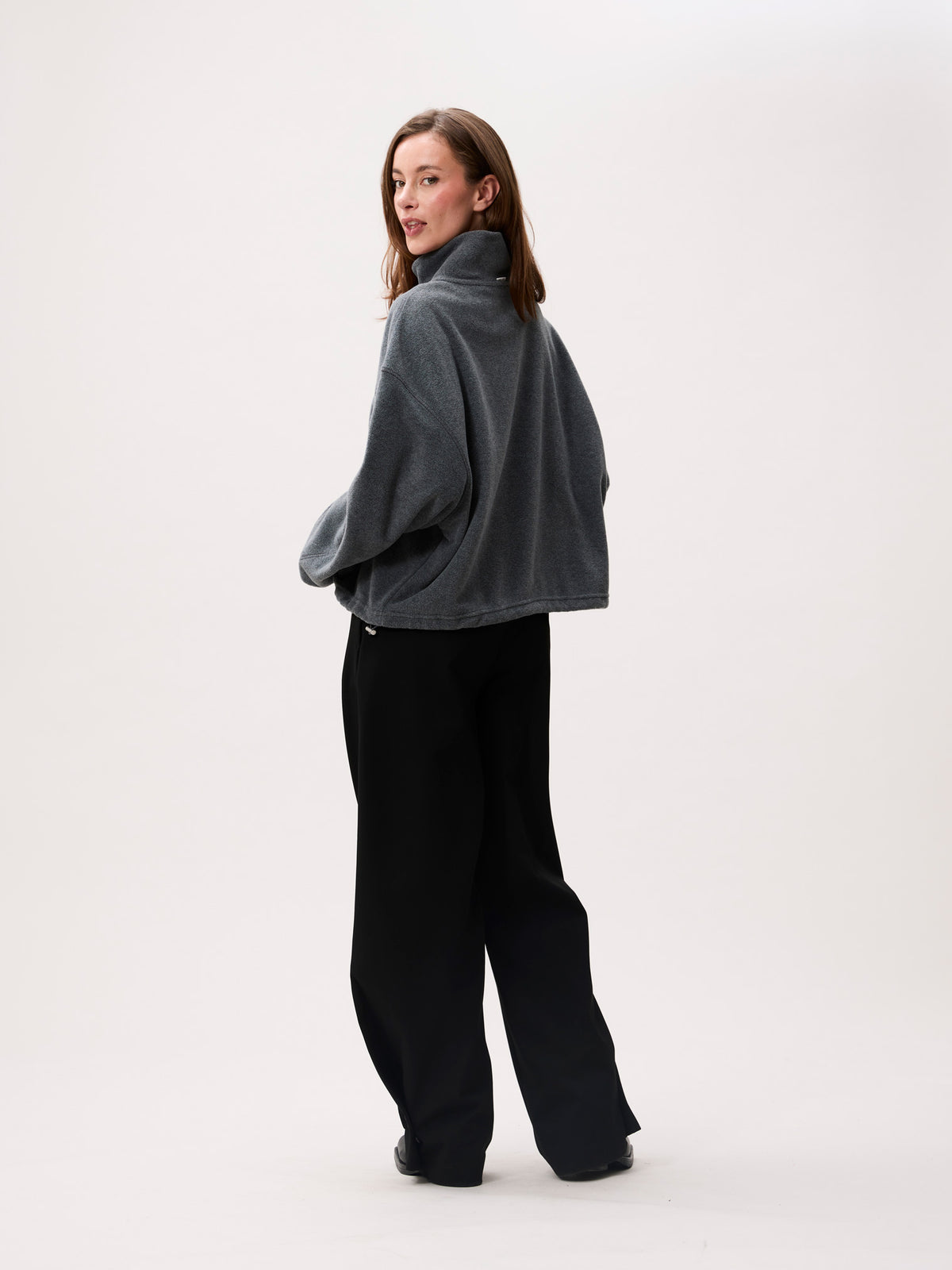 model draagt de sweater, achterkant met opstaande kraag zichtbaar