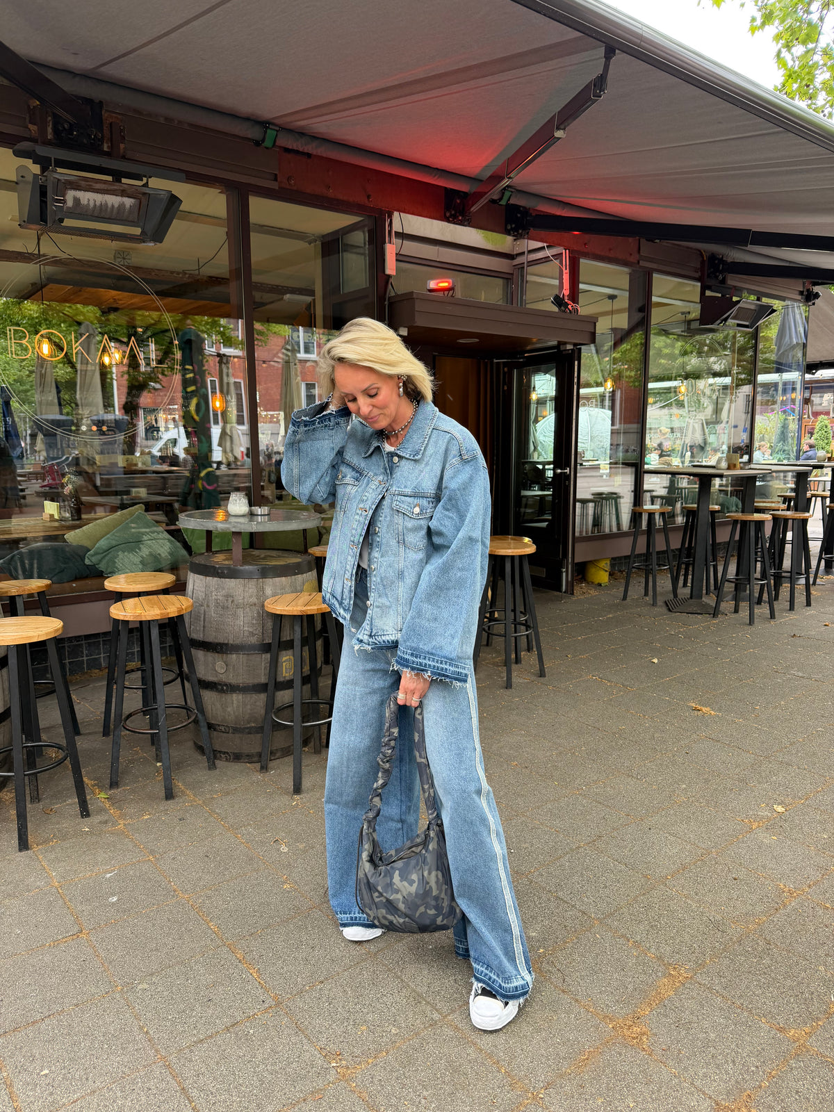 model draagt funky tyla jeans met denim jasje en sneakers op straat