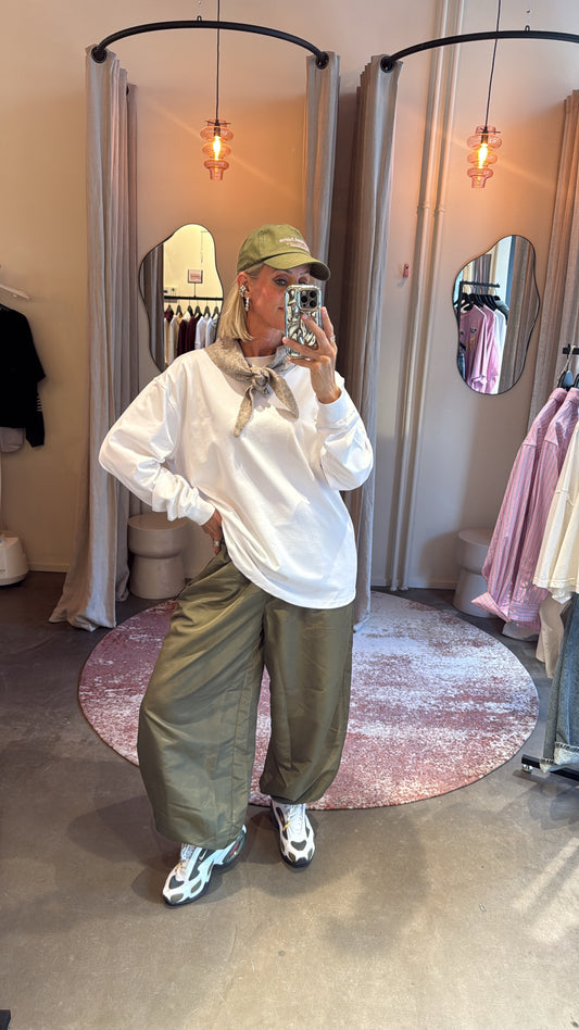model combineert de army harem pant met oversized witte longsleeve en pet