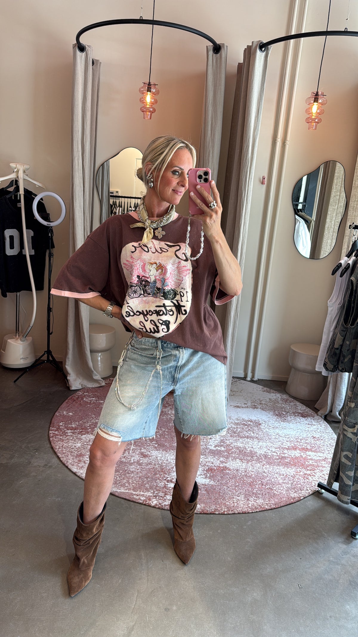 model combineert sjaaltje om de nek met denim short en suède laarzen