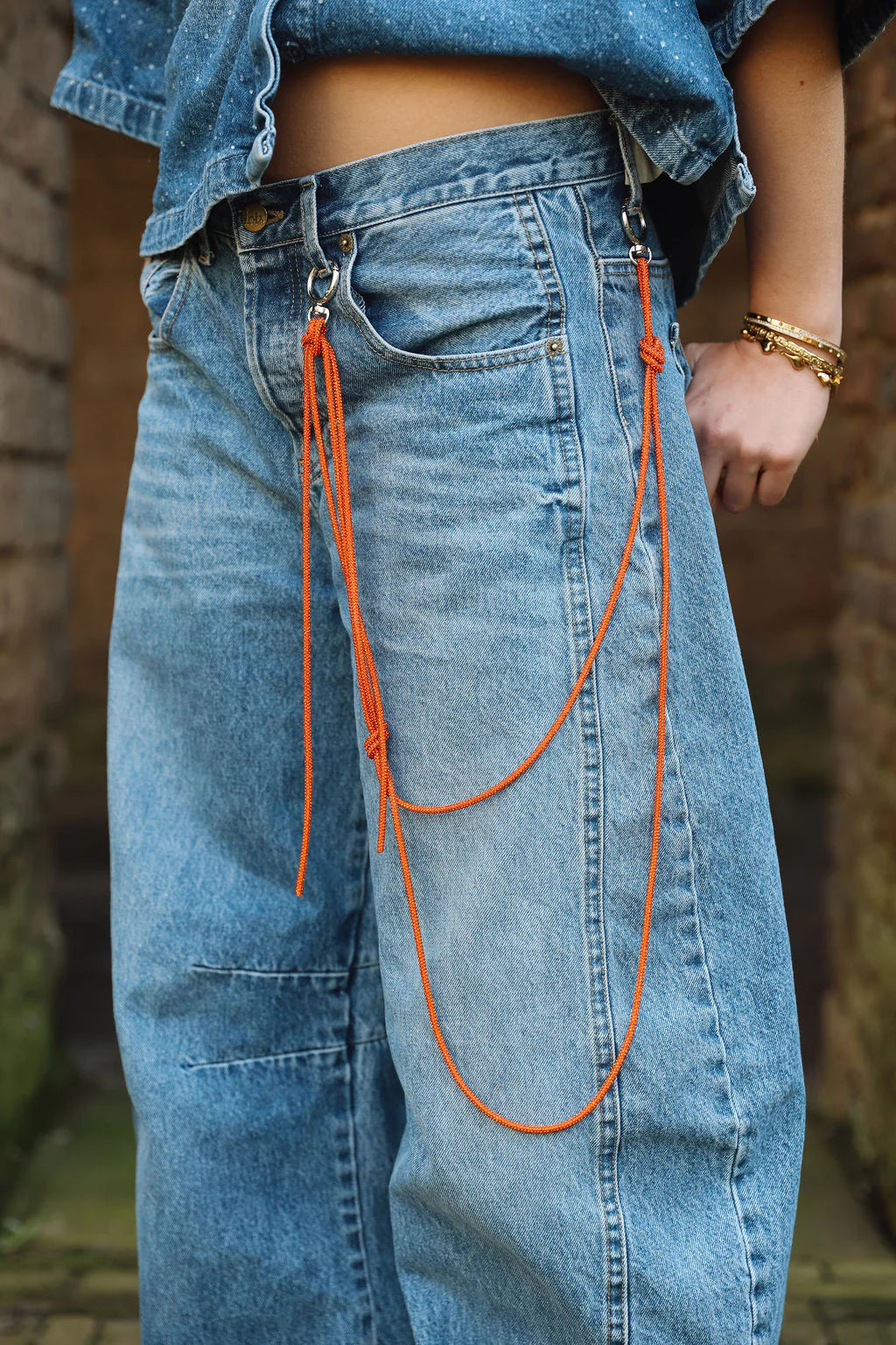 glitter chain orange van maasvan. gedragen aan broeklus over spijkerbroek, detail
