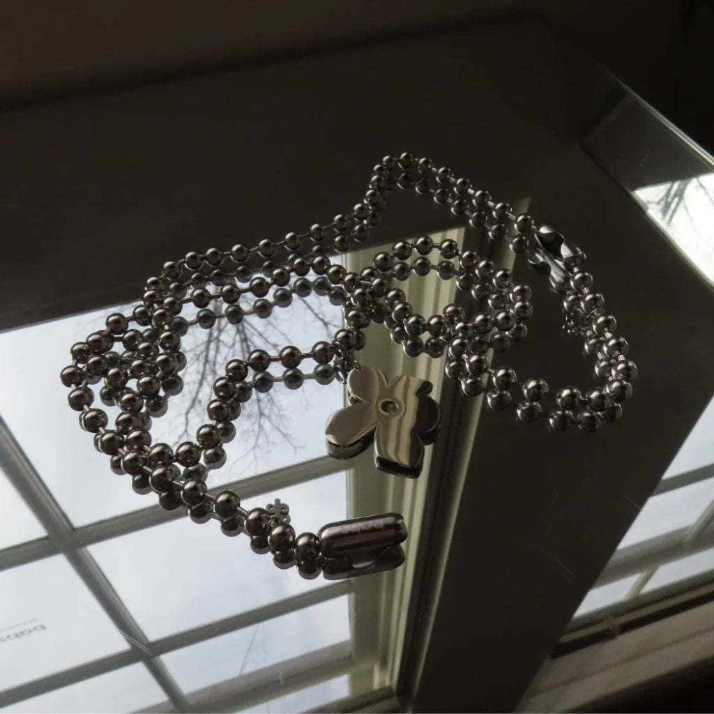 detail van de petal pendant aan de zilveren ketting op spiegelende ondergrond