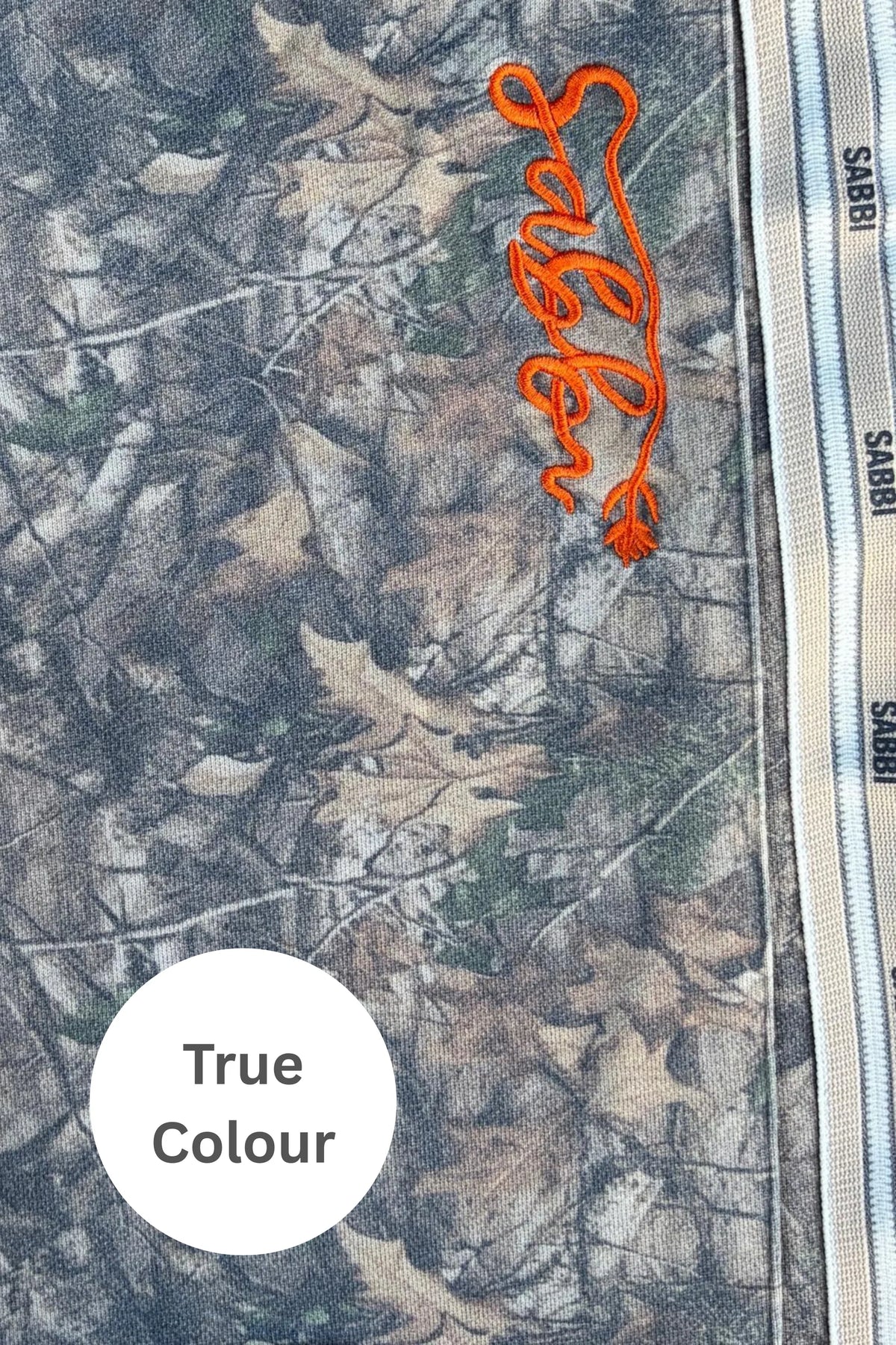 close-up van camo stof met oranje sabbi borduursel, ware kleurweergave