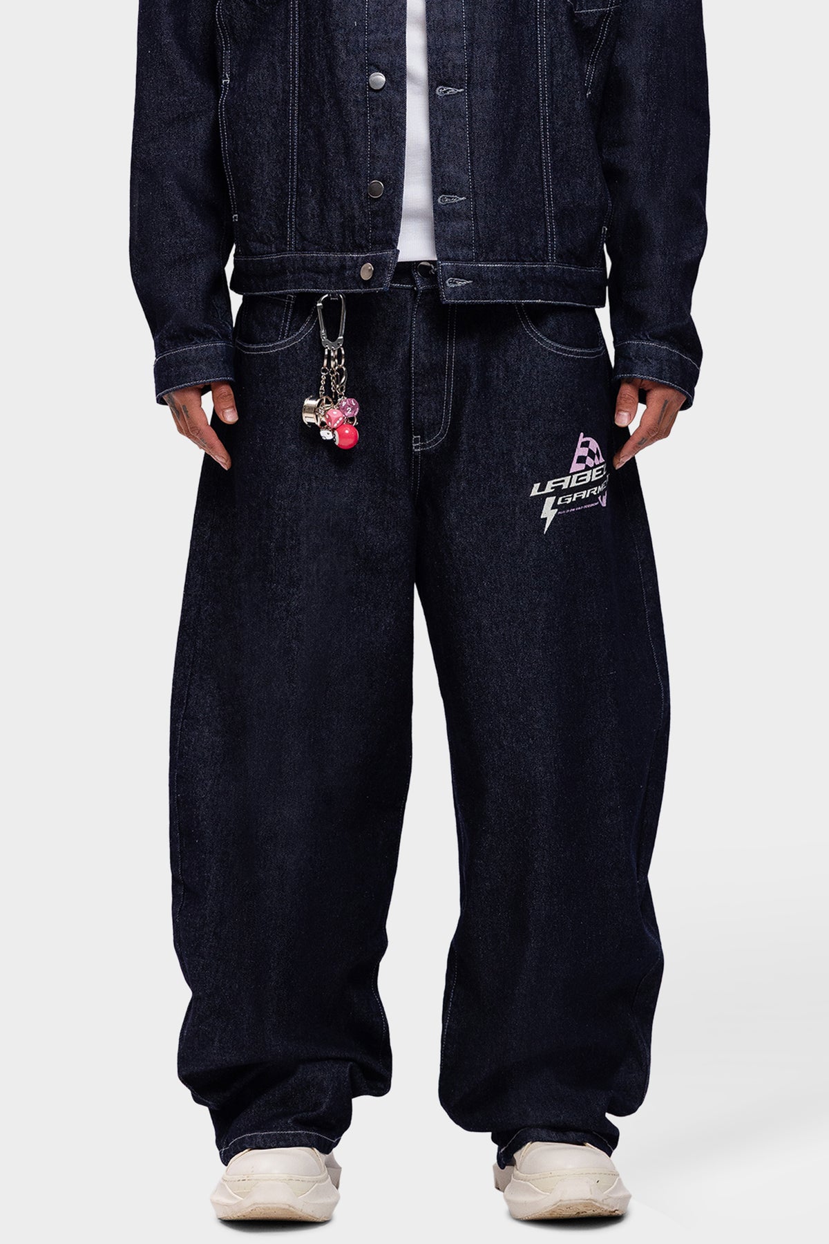 detail van voorkant pitlane denim pants met print en sleutelhanger aan de broeksband