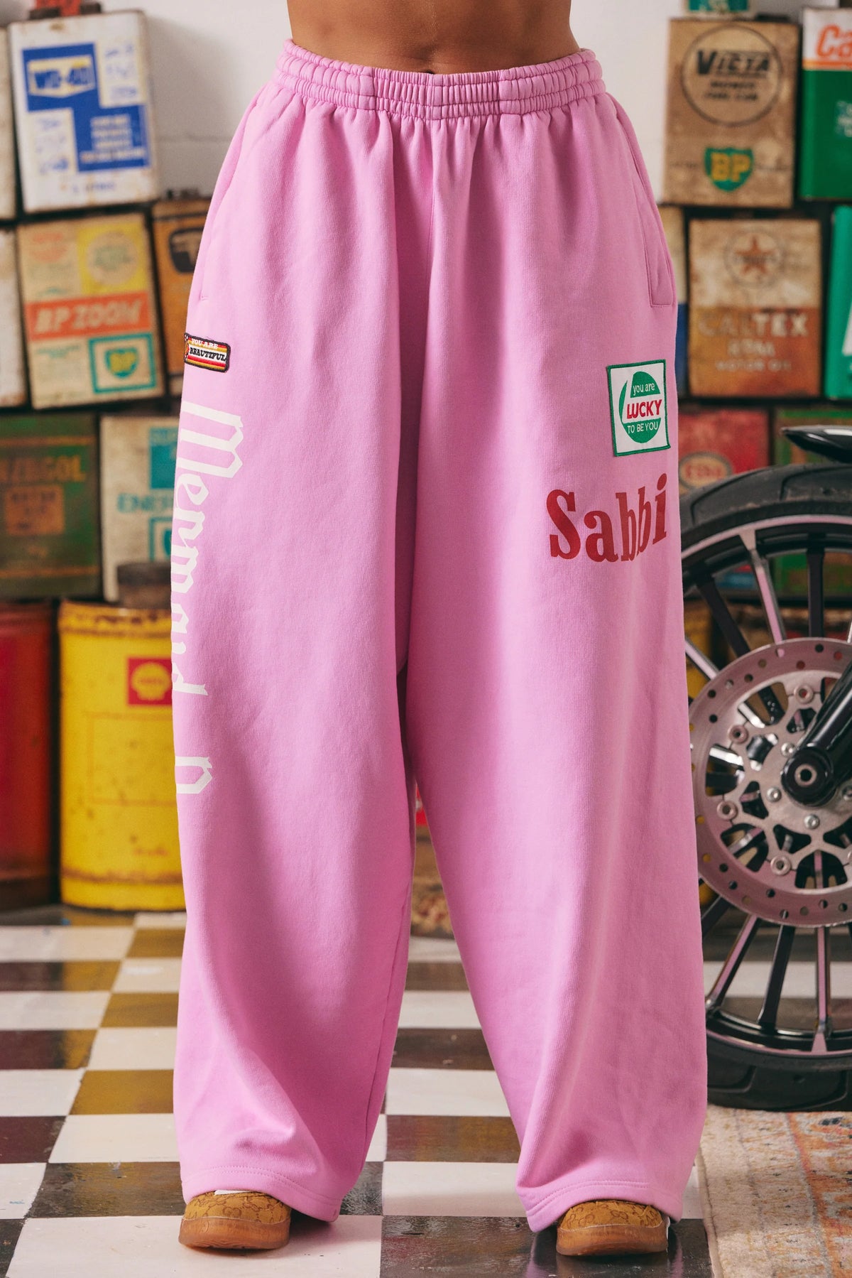 close-up vooraanzicht van roze sweatpants met sabbi logo en racing patches
