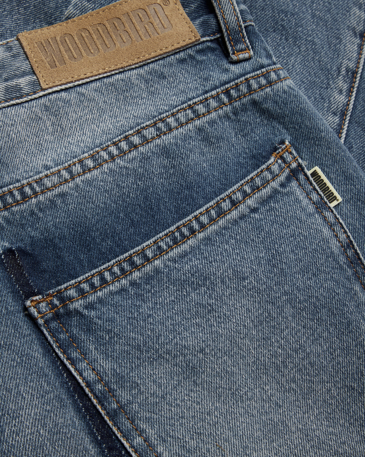 close-up van achterzak en leren label met woodbird logo