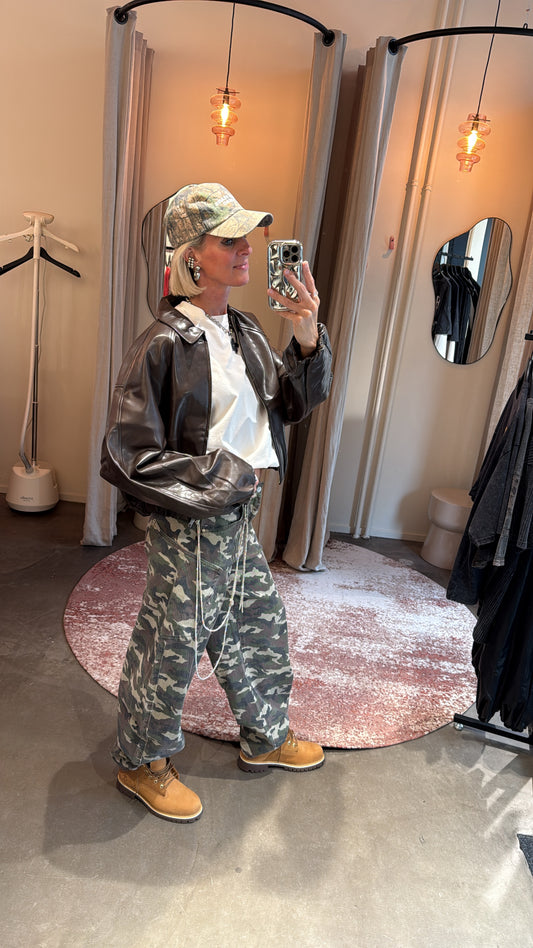 model draagt army balloon jeans met leren jack, zijaanzicht in paskamer