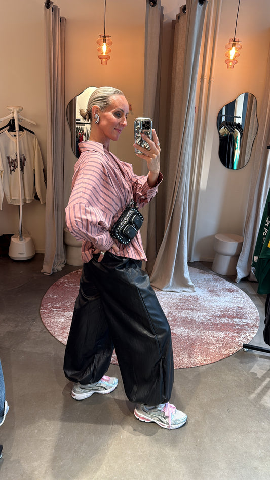 zijaanzicht van de balloon pants in leerlook, gecombineerd met gestreepte blouse en sneakers