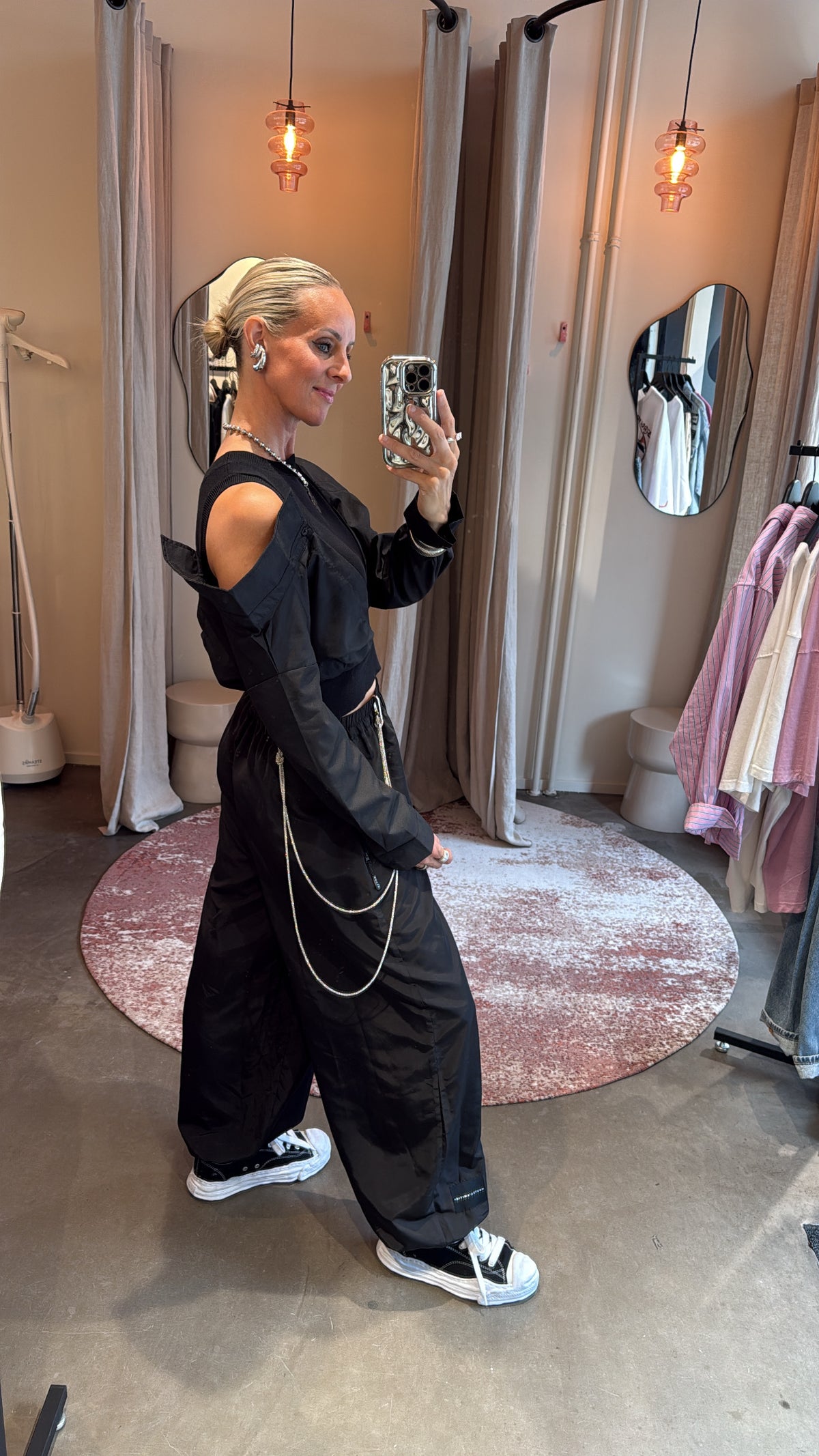 model draagt de broek in zijaanzicht, met sneakers en ketting als accessoire