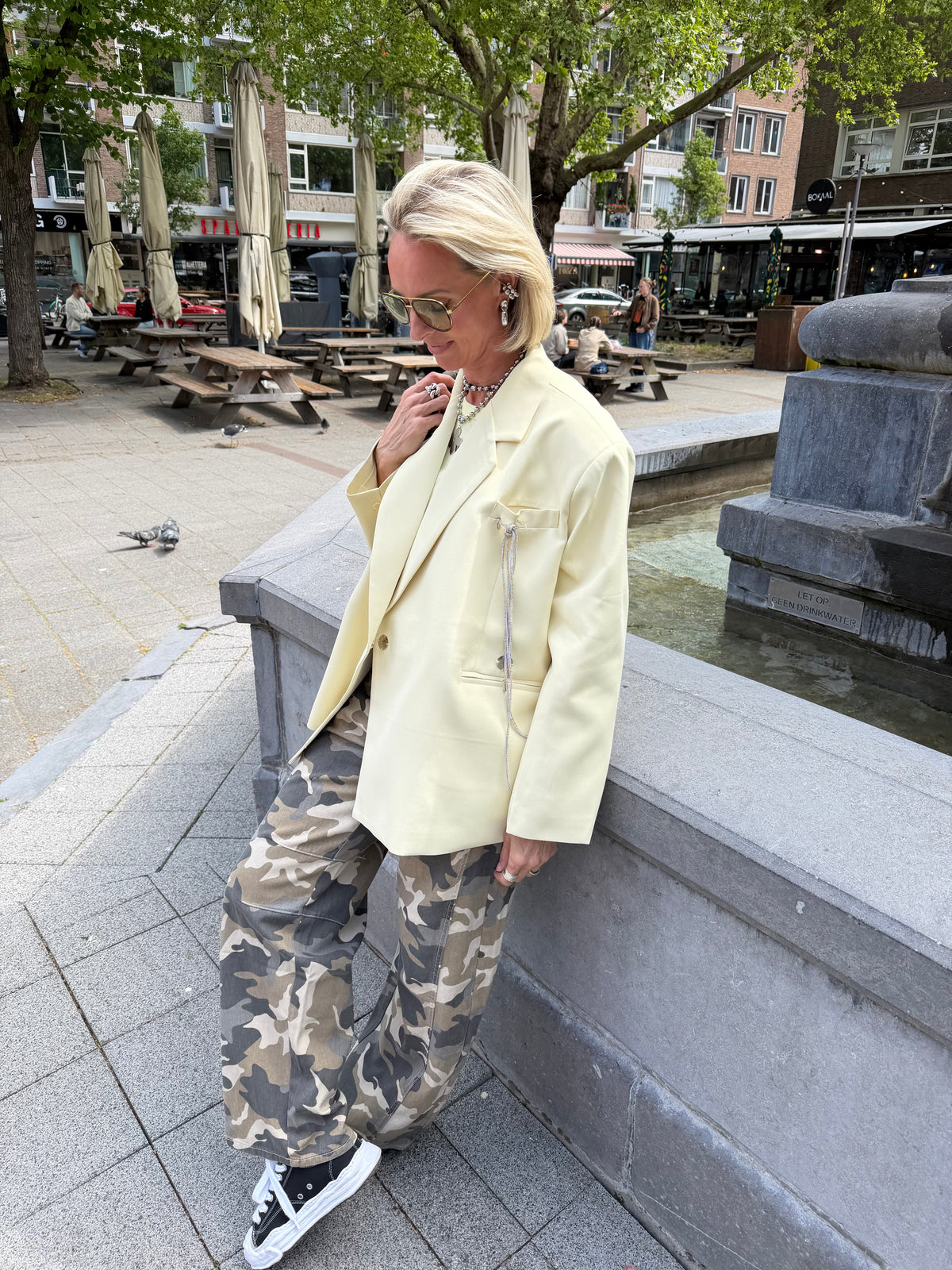 zijaanzicht model met oversized blazer geel en camo broek, buiten op straat