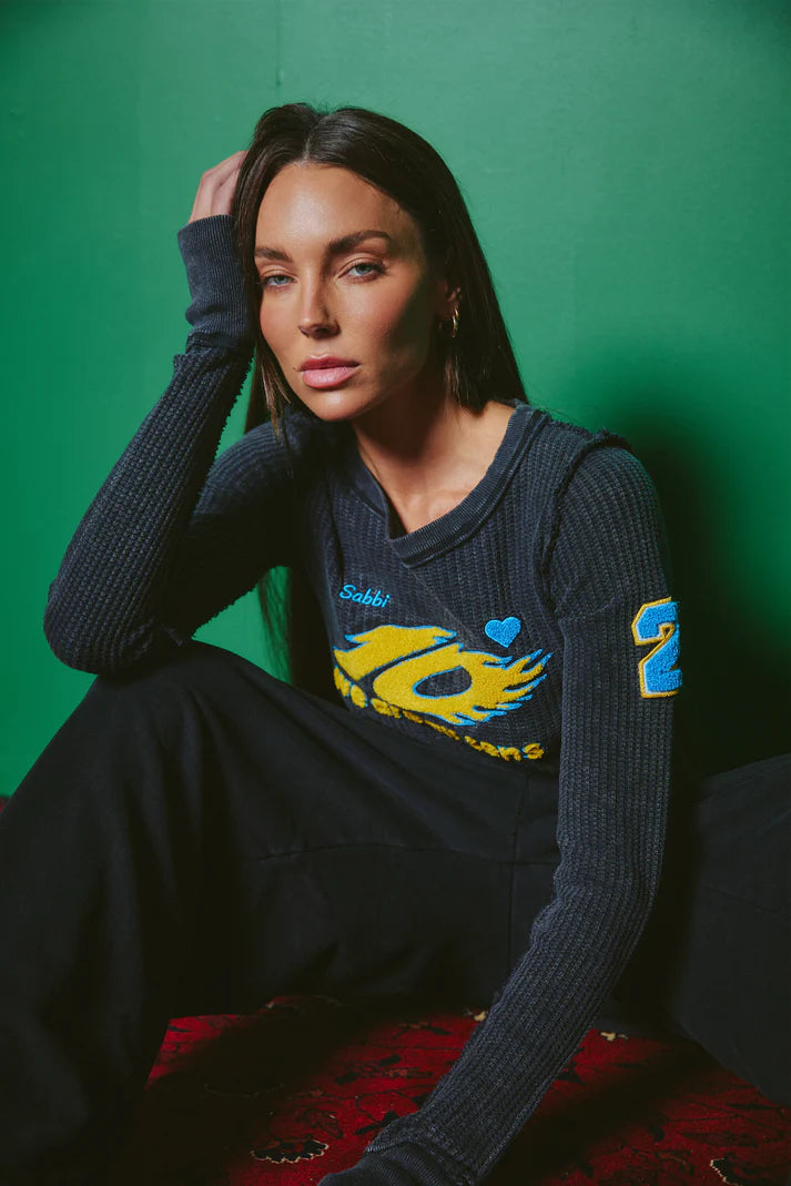 model zittend met top, close-up van kraag en mouw met patch detail