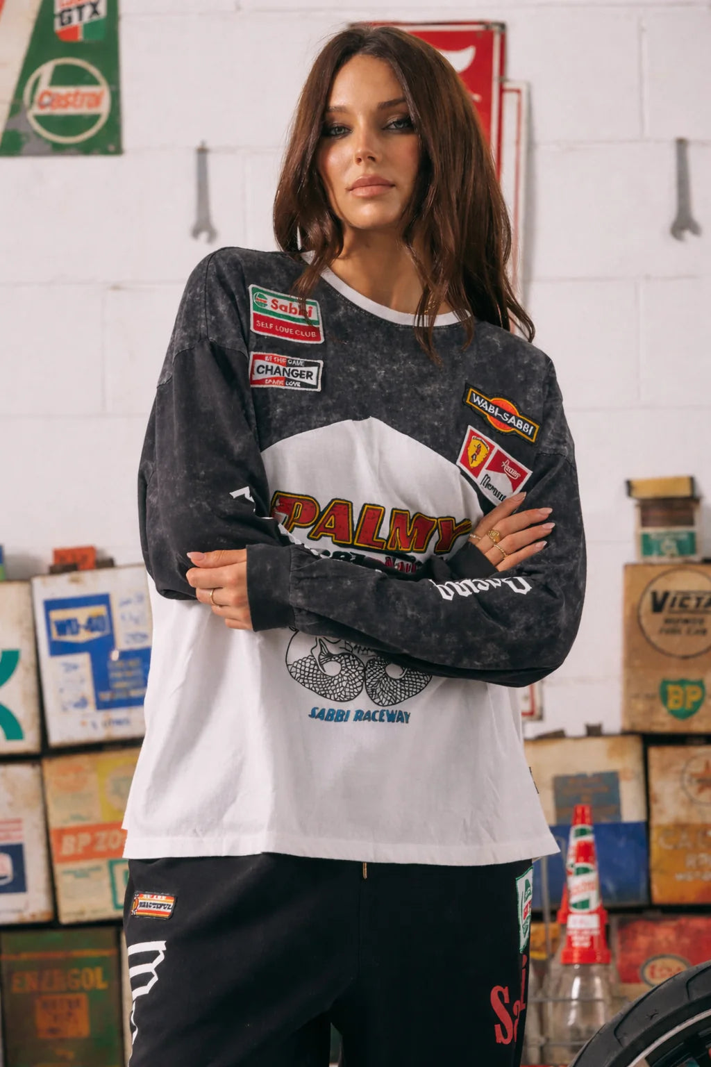 model met armen over elkaar in mermaid racing tee, close-up van patches en print op borst